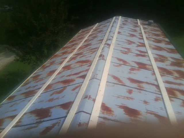 Rusted metal roof panels with new wood purlins before replacement — Storm Damage Roof Repair in Whiteford by Roofing Brothers