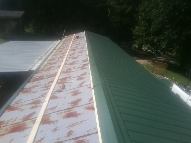 Old rusted panels beside newly installed green metal roofing — Wind Damage Roof Repair by Roofing Brothers in Whiteford