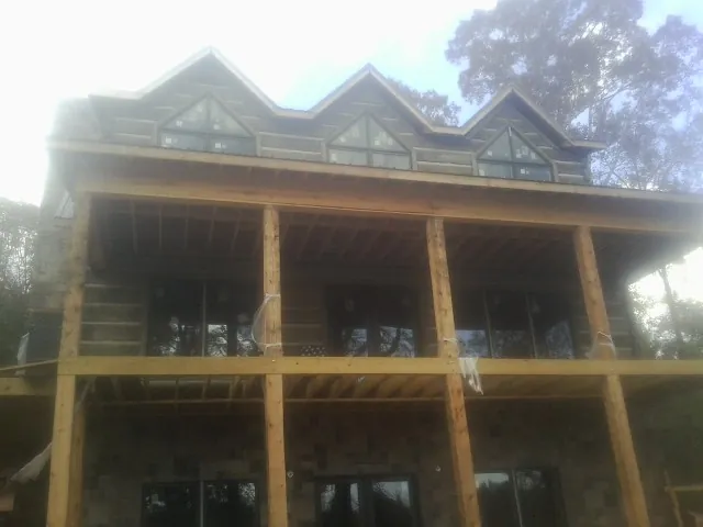 Dormers and porch framing on a large log home under construction — Roof Coating work by our crew in Whiteford
