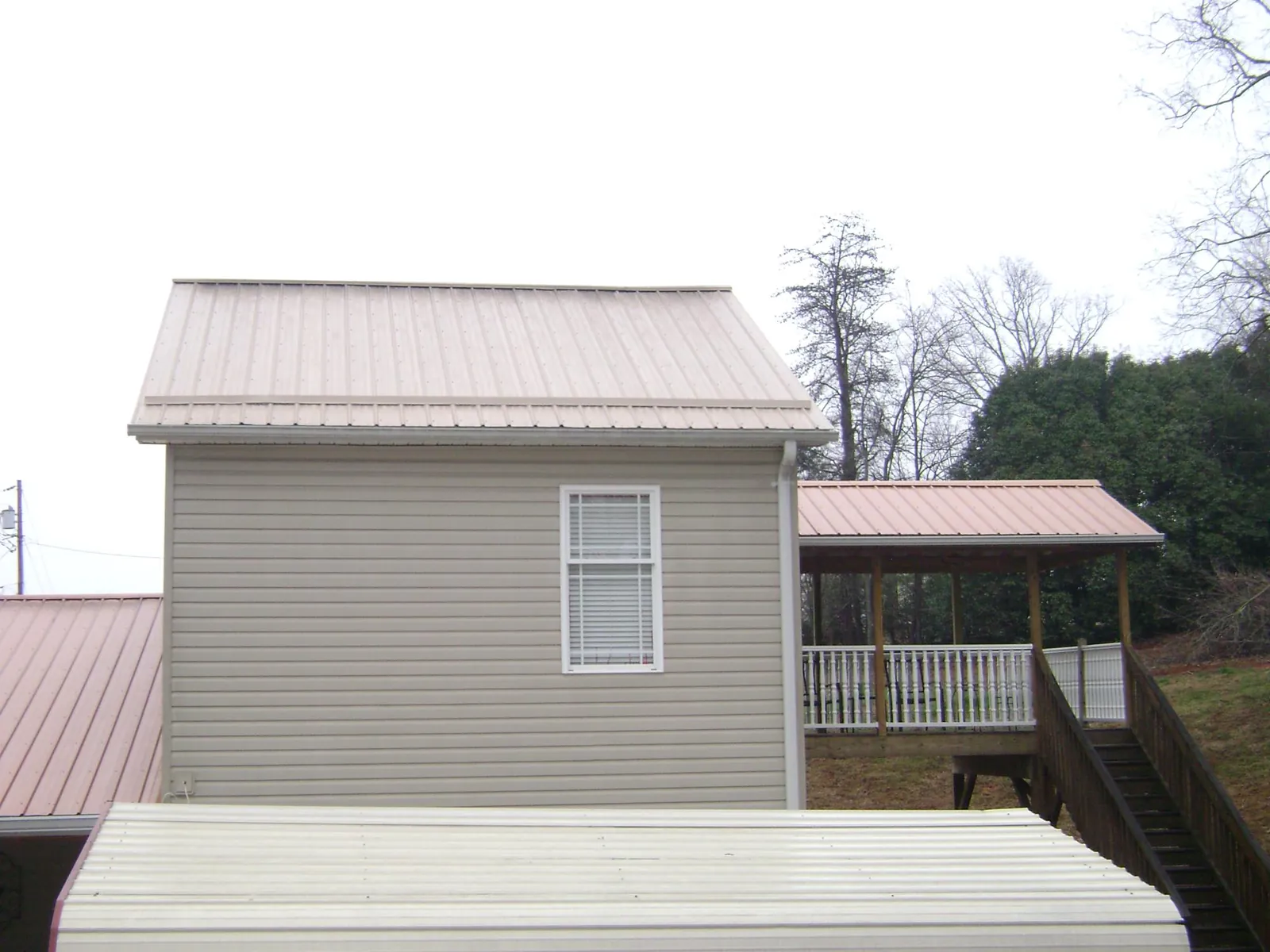 Tan metal roofs on a two story addition and attached porch, from a Roof Replacement job in Whiteford