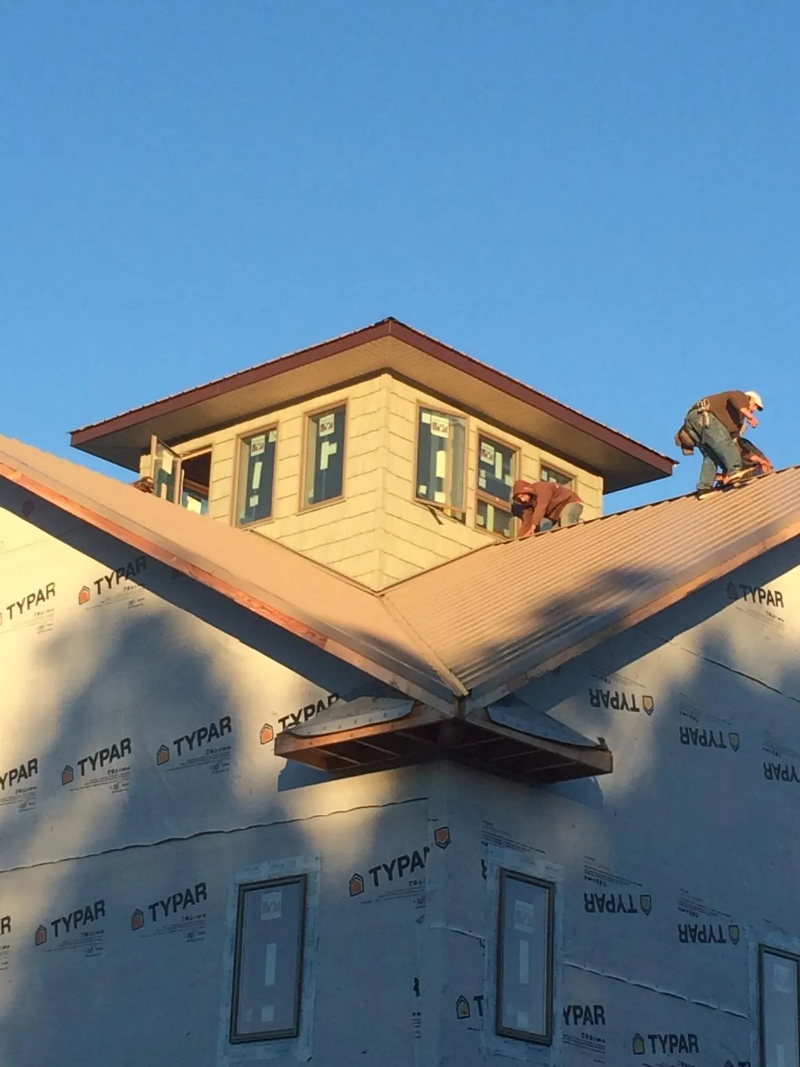 Roofers working around a rooftop cupola on a new metal roof at sunset — Roof Waterproofing in Whiteford by Roofing Brothers